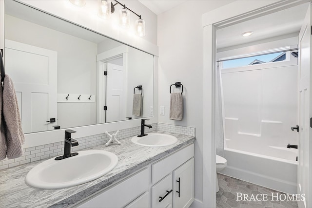 bathroom featuring double vanity, shower / bath combo with shower curtain, a sink, and toilet