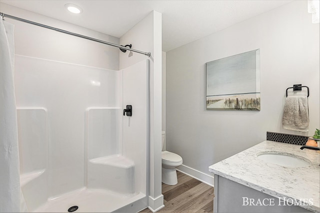 bathroom with vanity, a shower stall, toilet, and wood finished floors