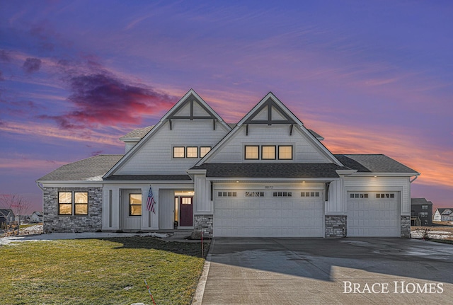 shingle-style home with driveway, a lawn, stone siding, roof with shingles, and board and batten siding