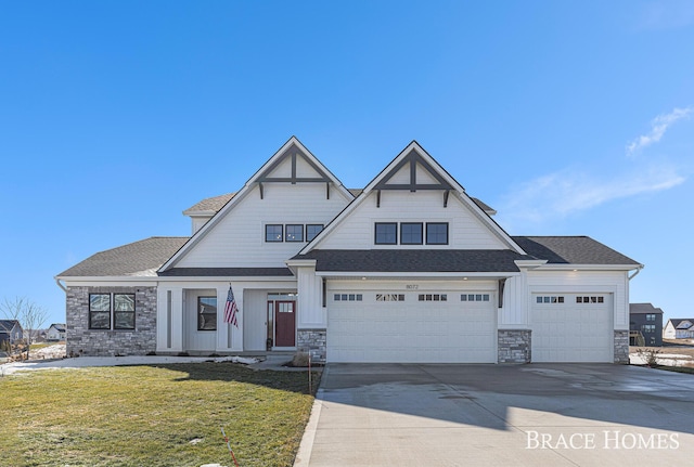 view of front of home featuring a shingled roof, stone siding, driveway, board and batten siding, and a front yard