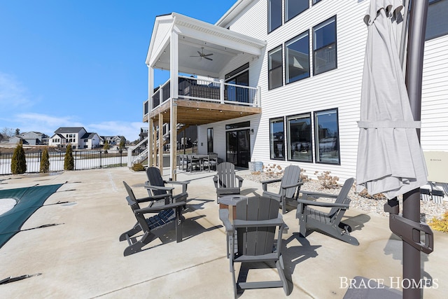 view of patio / terrace with a fire pit, a balcony, ceiling fan, fence, and outdoor dining area