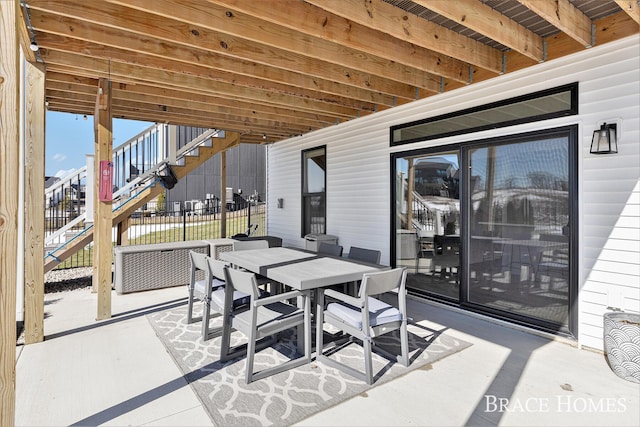 view of patio with outdoor dining area, stairway, and fence