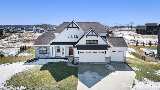 view of front of property featuring stone siding, driveway, and fence