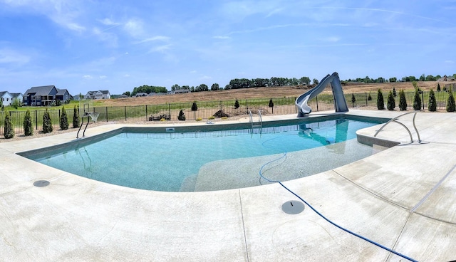 view of pool with a water slide, fence, and a fenced in pool