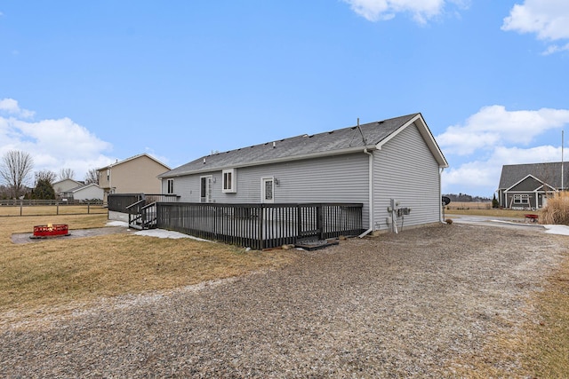 back of house with fence, a deck, and a yard