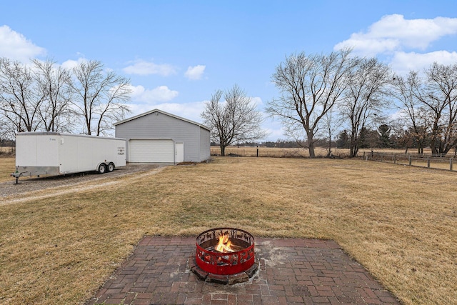 view of yard featuring an outbuilding, an outdoor fire pit, a detached garage, and fence