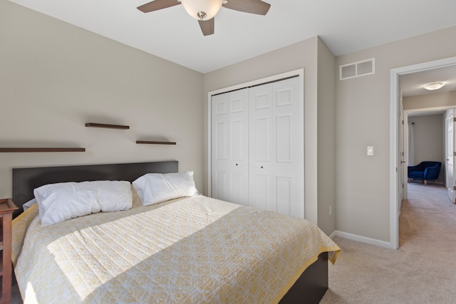 bedroom with baseboards, visible vents, a ceiling fan, light colored carpet, and a closet