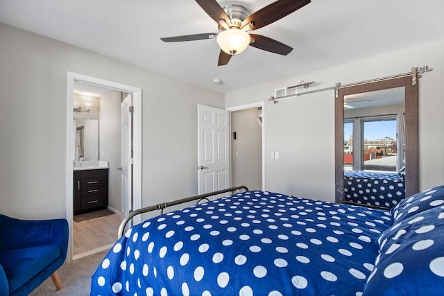 bedroom featuring carpet, a barn door, ceiling fan, and connected bathroom