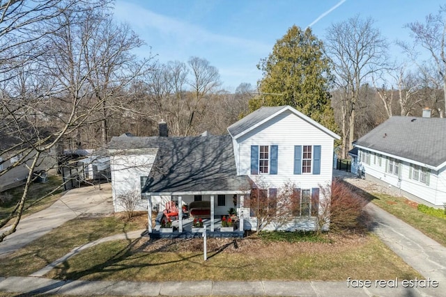 view of front of house with a porch, an attached carport, driveway, and a chimney