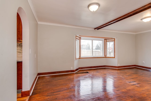 empty room featuring arched walkways, crown molding, baseboards, and hardwood / wood-style flooring