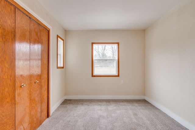 unfurnished bedroom with baseboards, a closet, and light colored carpet