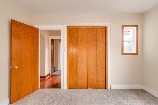 unfurnished bedroom with carpet, a closet, and baseboards