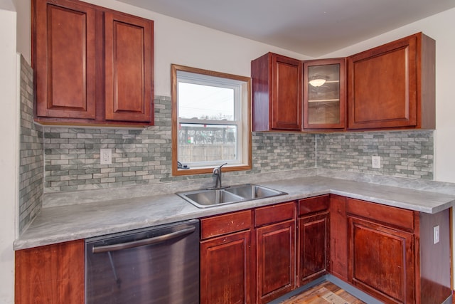 kitchen featuring a sink, reddish brown cabinets, decorative backsplash, and dishwasher