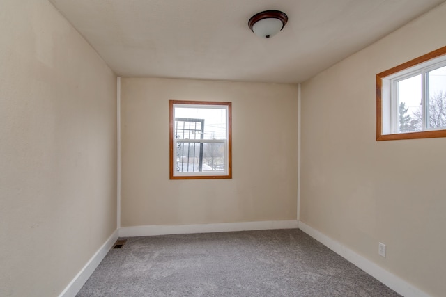 carpeted empty room featuring visible vents and baseboards