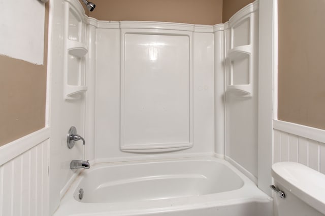 bathroom featuring toilet, shower / tub combination, and wainscoting