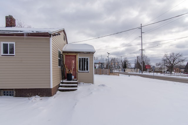 view of snow covered exterior featuring a chimney