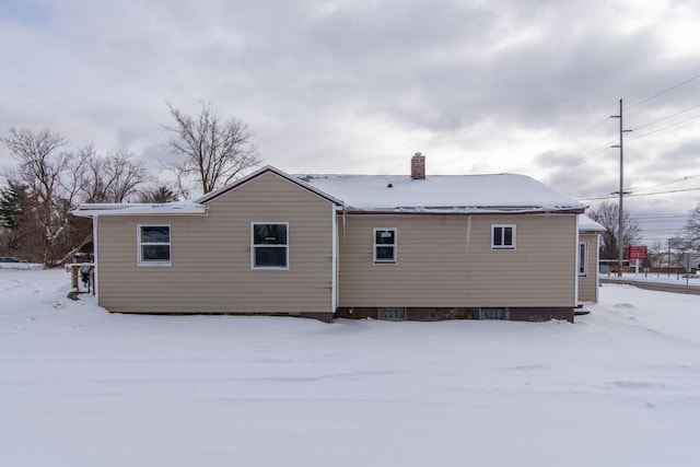 snow covered house featuring a chimney