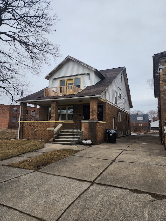 view of front of home featuring a porch, brick siding, and a balcony