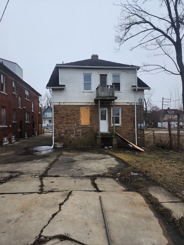 back of property with a chimney and a balcony