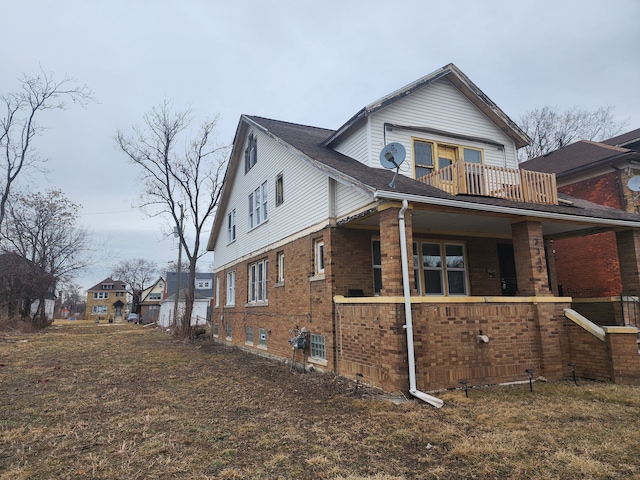 view of home's exterior with a balcony, a porch, and brick siding