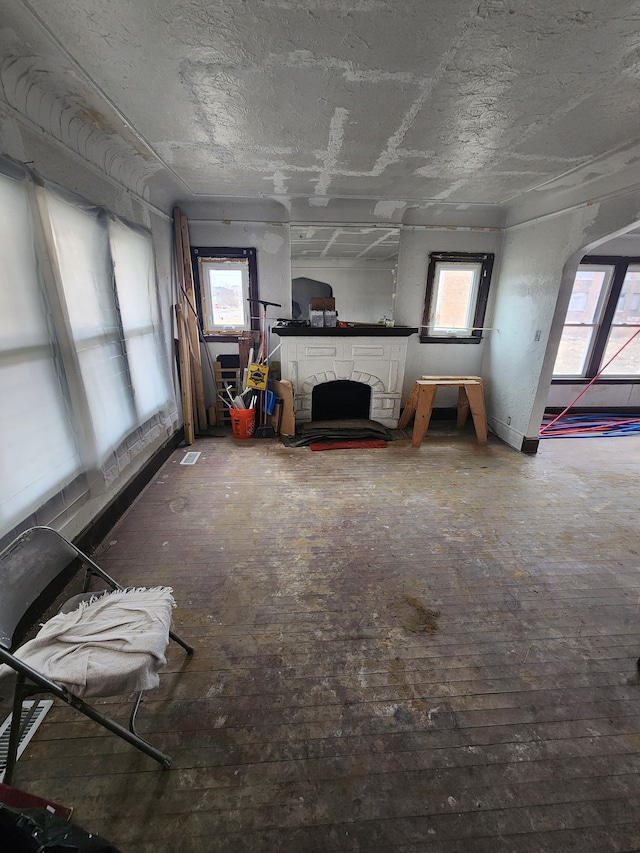 unfurnished living room with arched walkways, plenty of natural light, and a stone fireplace