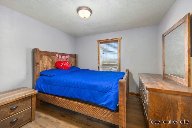 bedroom with a textured ceiling and wood finished floors