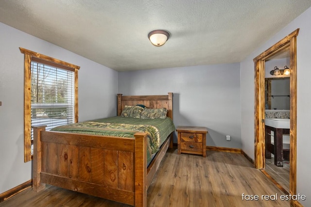 bedroom featuring a textured ceiling, baseboards, and wood finished floors