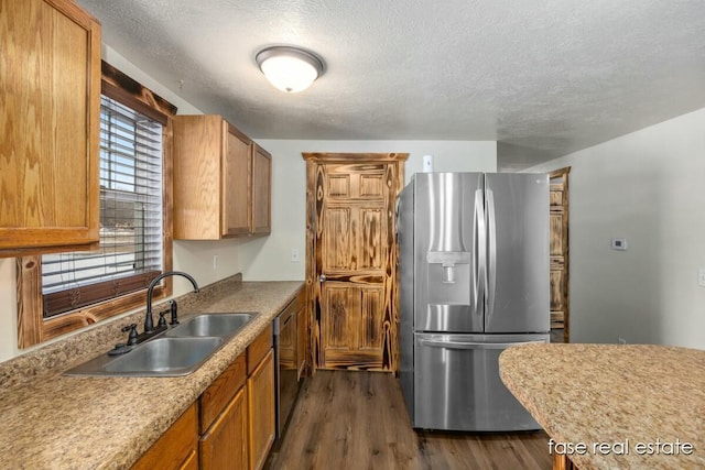 kitchen with dark wood-style floors, appliances with stainless steel finishes, brown cabinets, and a sink