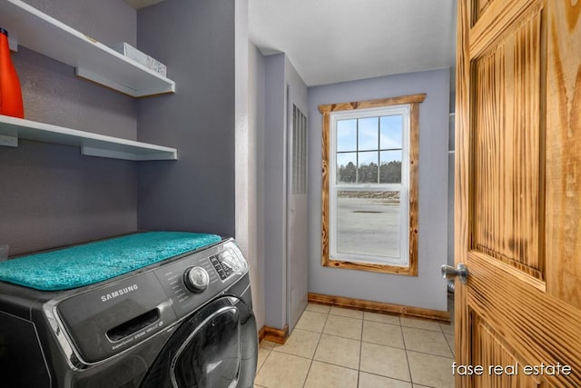 washroom featuring laundry area, baseboards, light tile patterned floors, and washer / clothes dryer