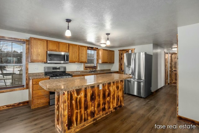 kitchen with appliances with stainless steel finishes, brown cabinetry, plenty of natural light, and a sink