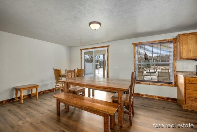 dining room featuring a textured ceiling, baseboards, and wood finished floors