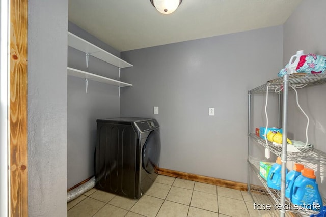 laundry area featuring laundry area, baseboards, light tile patterned floors, and washer / clothes dryer