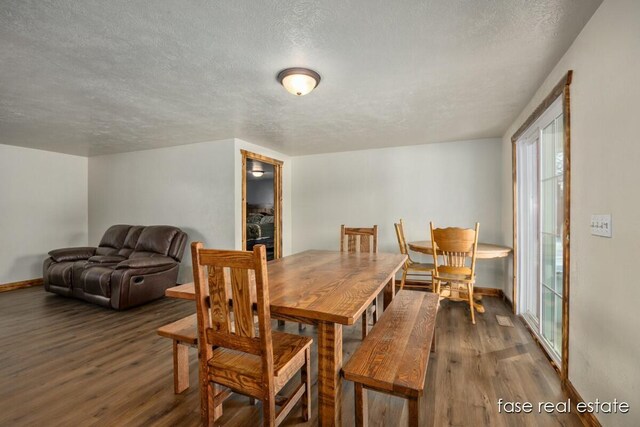 dining area featuring a textured ceiling, baseboards, and wood finished floors