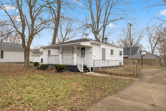 view of front facade with covered porch, a fenced front yard, and a front lawn