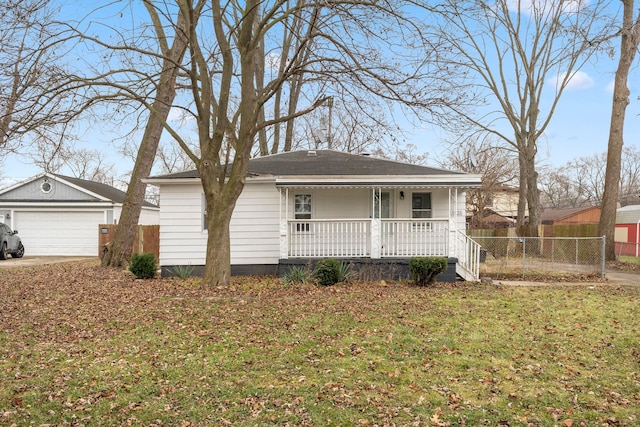 view of front of home with a porch, a front yard, fence, a garage, and an outdoor structure