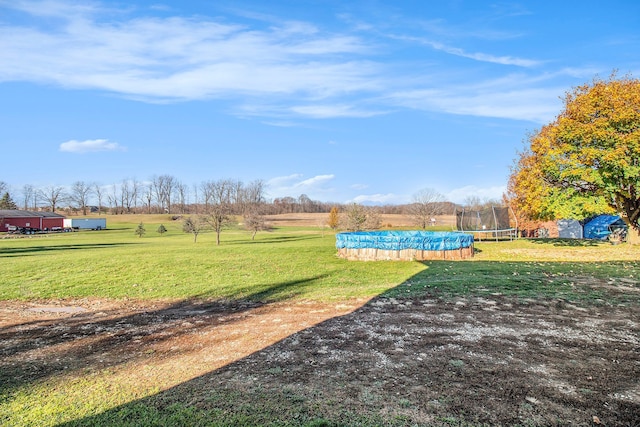 view of property's community with a trampoline, a rural view, and a yard