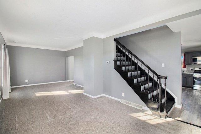 staircase featuring carpet floors, visible vents, and baseboards