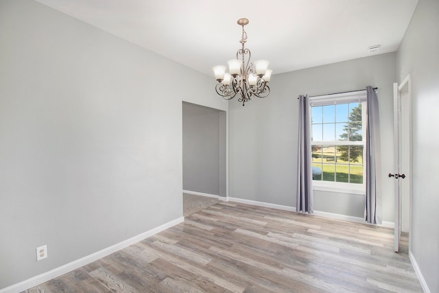 unfurnished room with light wood finished floors, baseboards, and an inviting chandelier