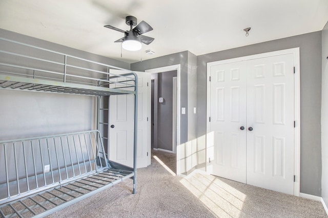 unfurnished bedroom featuring ceiling fan, baseboards, a closet, and carpet flooring