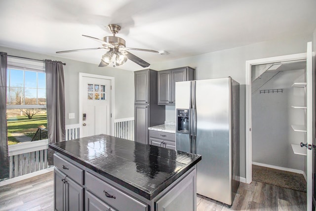 kitchen featuring dark countertops, gray cabinets, stainless steel fridge, and light wood-style flooring