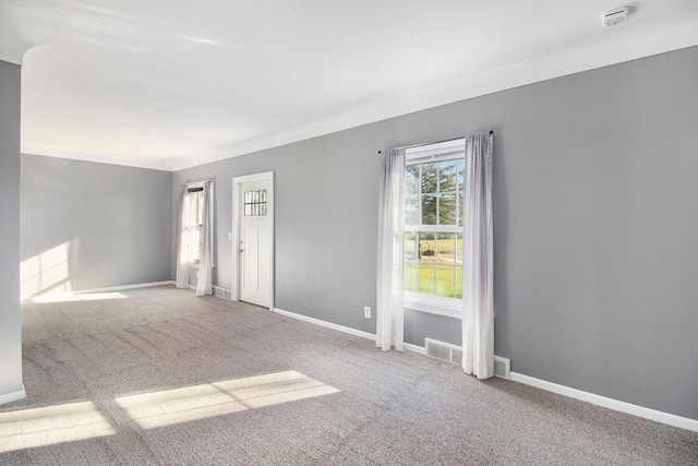 carpeted empty room featuring visible vents and baseboards