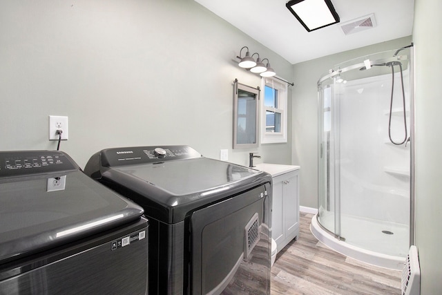 clothes washing area featuring washer and clothes dryer, visible vents, baseboard heating, a sink, and laundry area