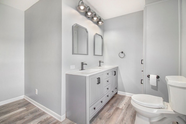 bathroom featuring wood finished floors, a sink, toilet, and baseboards