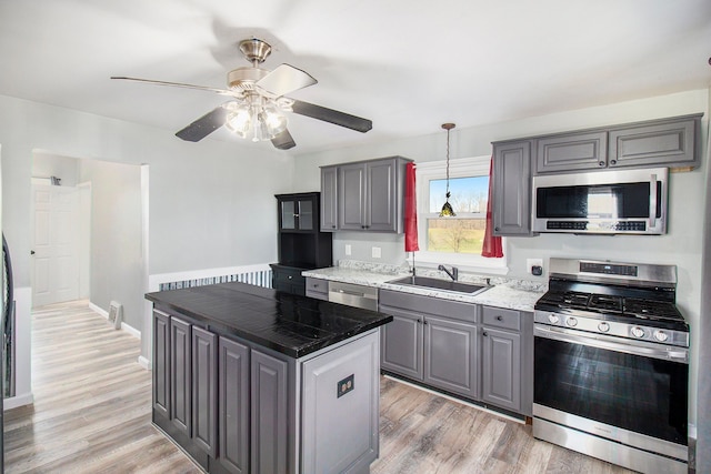 kitchen with a sink, stainless steel appliances, light wood-type flooring, and gray cabinets