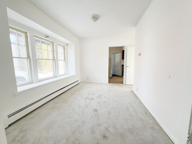 empty room featuring light carpet, baseboard heating, and baseboards