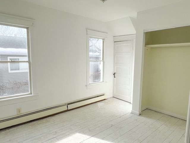 unfurnished bedroom with a baseboard heating unit, a closet, and light wood finished floors