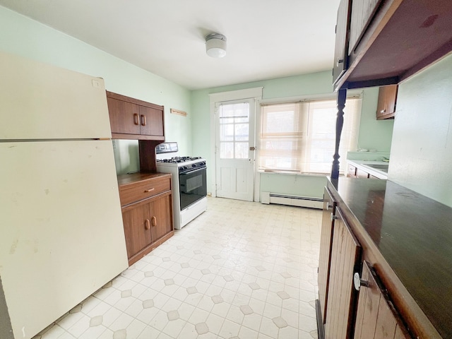 kitchen featuring a baseboard heating unit, light floors, white appliances, and dark countertops