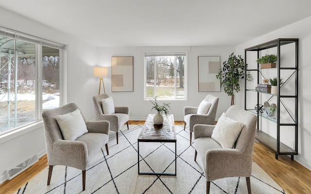 living area with plenty of natural light, wood finished floors, and visible vents