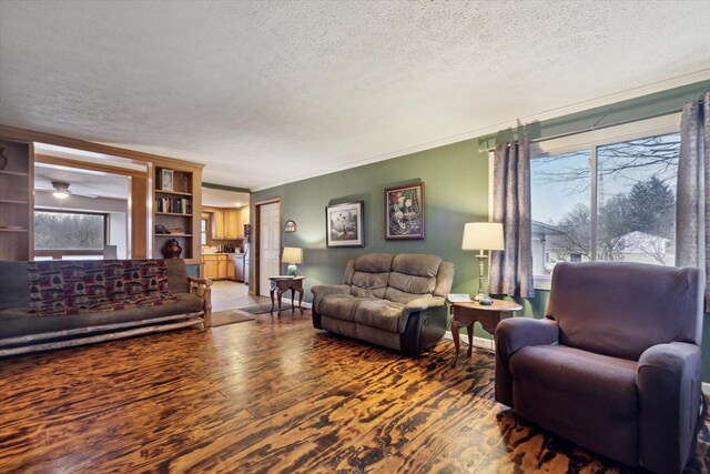 living room with ornamental molding, a textured ceiling, baseboards, and wood finished floors