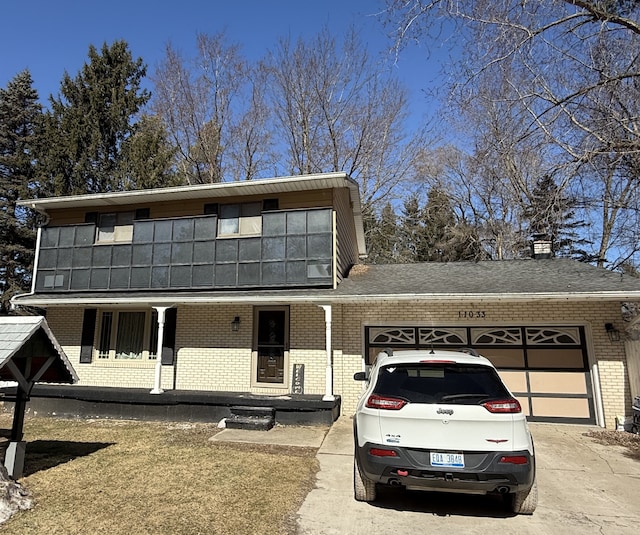 view of front of house featuring driveway, covered porch, roof with shingles, an attached garage, and brick siding